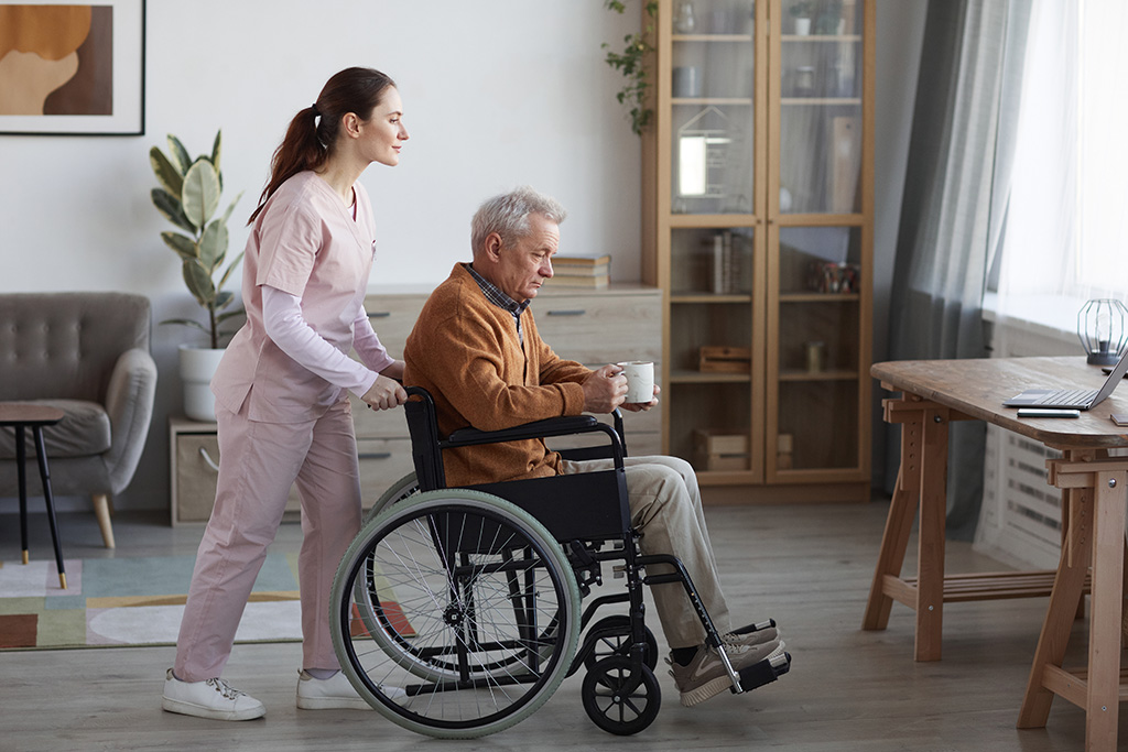 femme accompagnante de vie pousse une personne âgée dans un fauteuil roulant